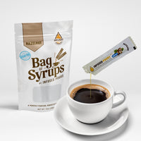 Bag of sugar free hazelnut syrup packets pouring into a coffee cup